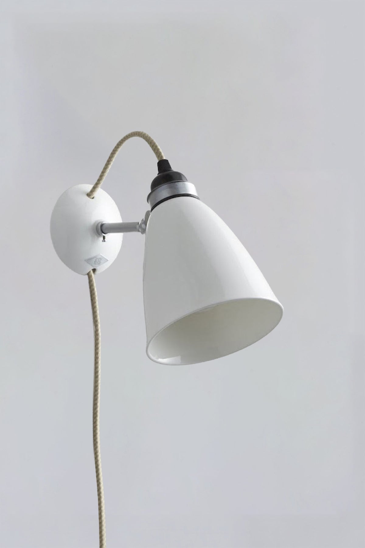 White wall-mounted lamp with a plug on a plain gray background