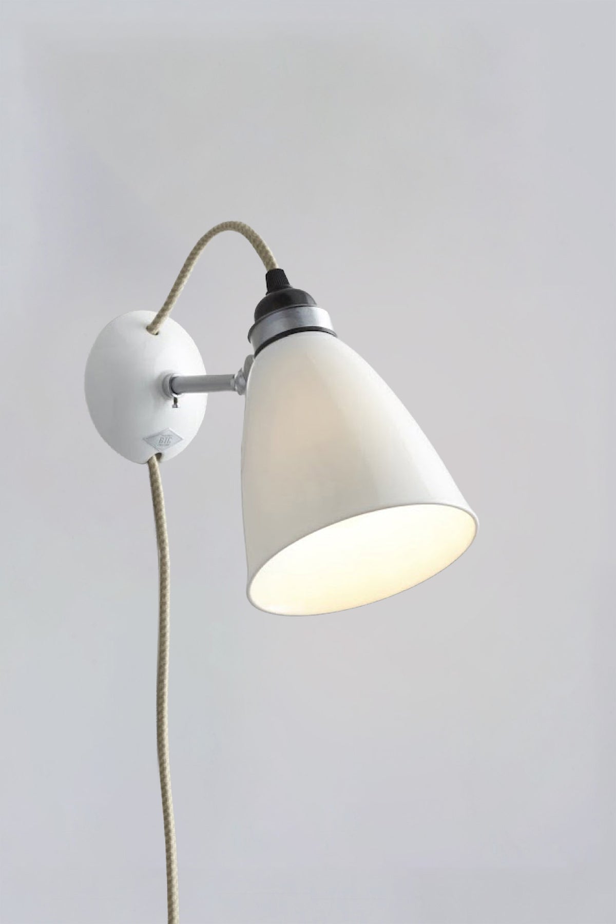 Wall-mounted lamp with white shade and visible bulb on a plain wall