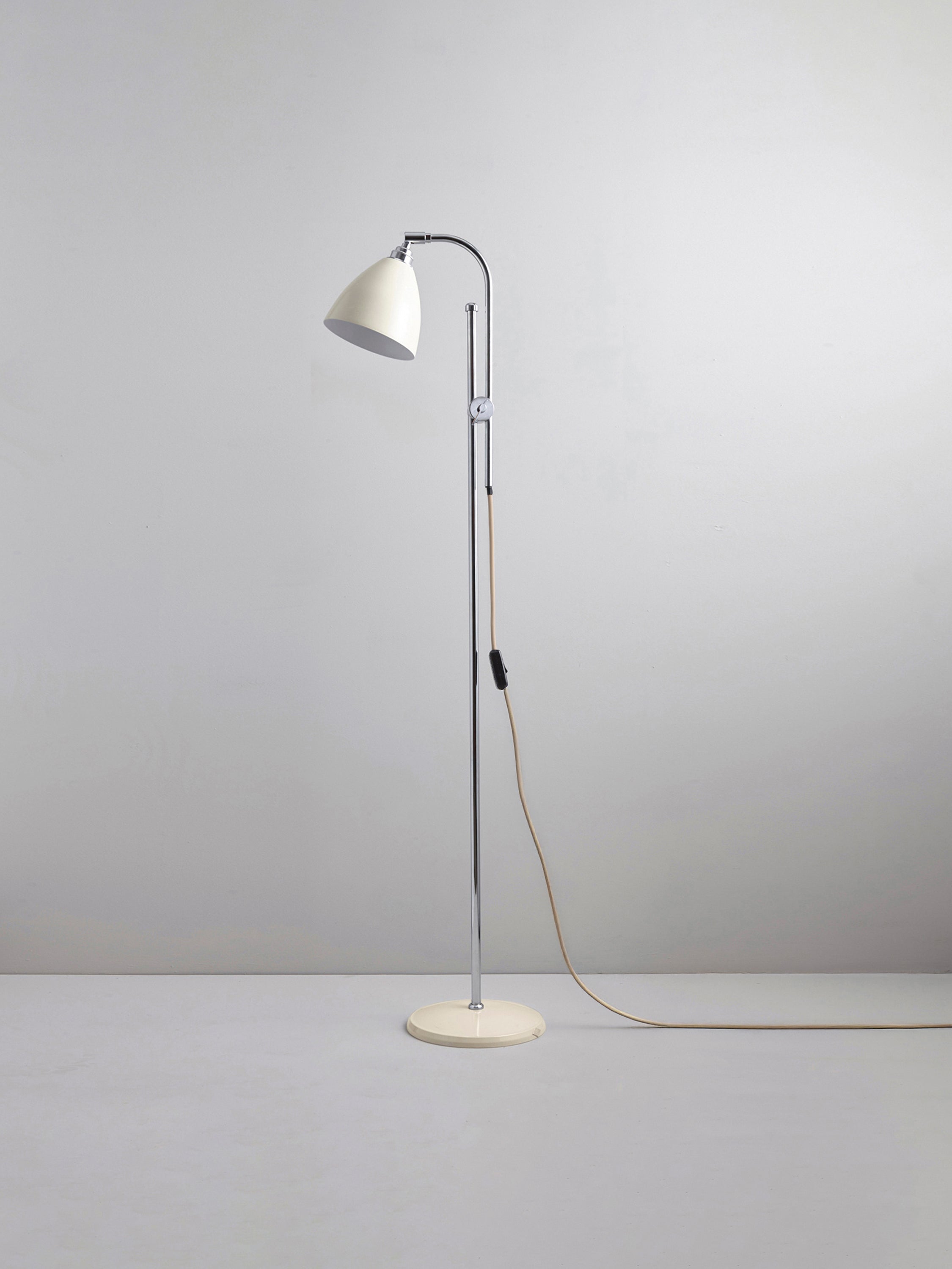 Floor lamp with white shade and base on a plain background