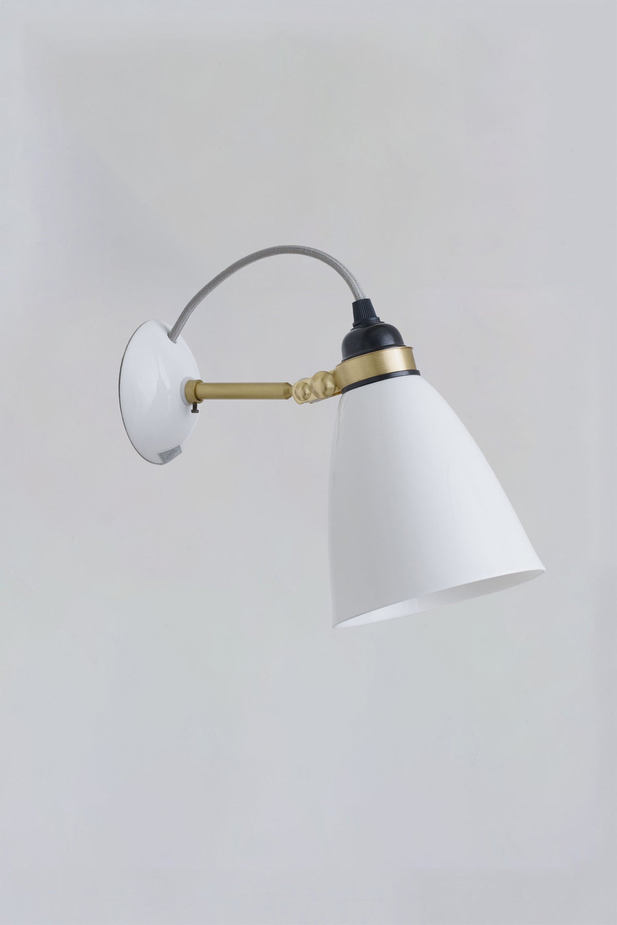 A wall-mounted Hector 30 light with a white shade and brass detailing, against a plain background.