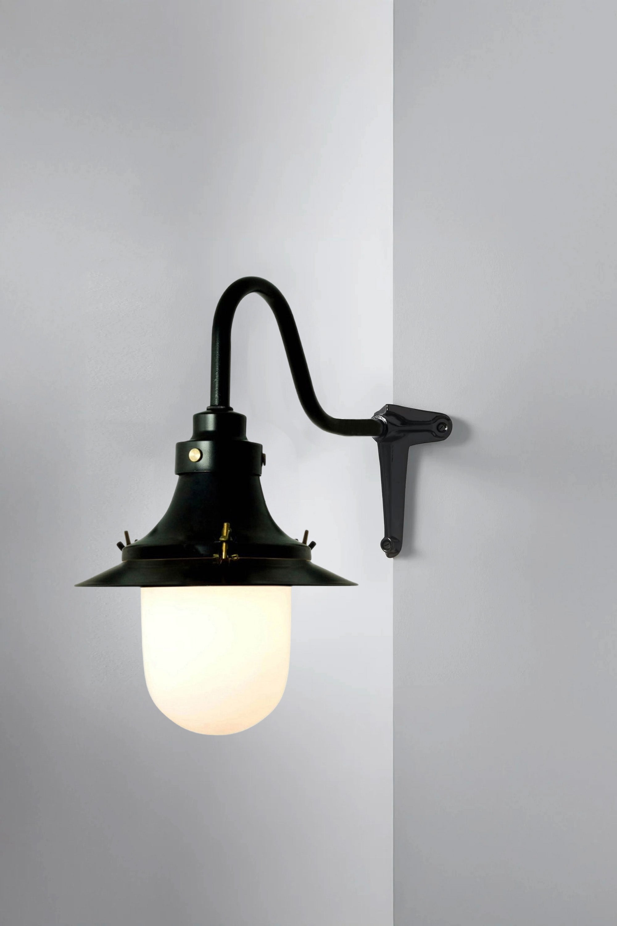 Black wall-mounted lamp with a white glass shade on a gray background