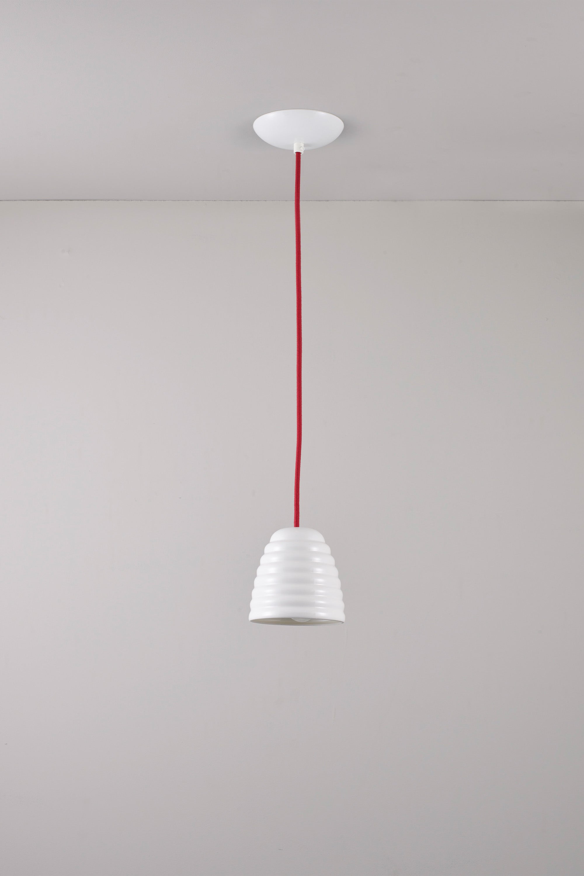 White pendant light with red cord against a gray background