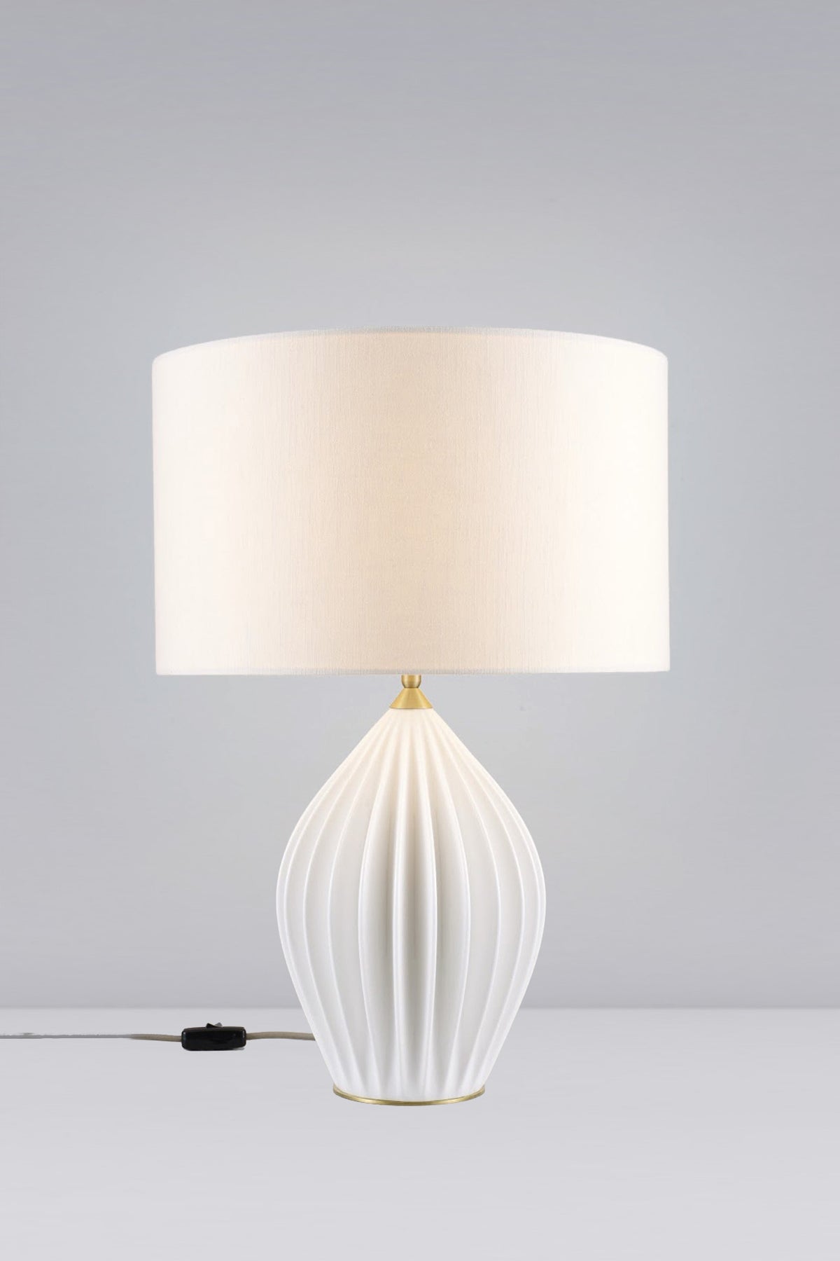 Fin King table light with a white bone china base and fabric shade, illuminated.