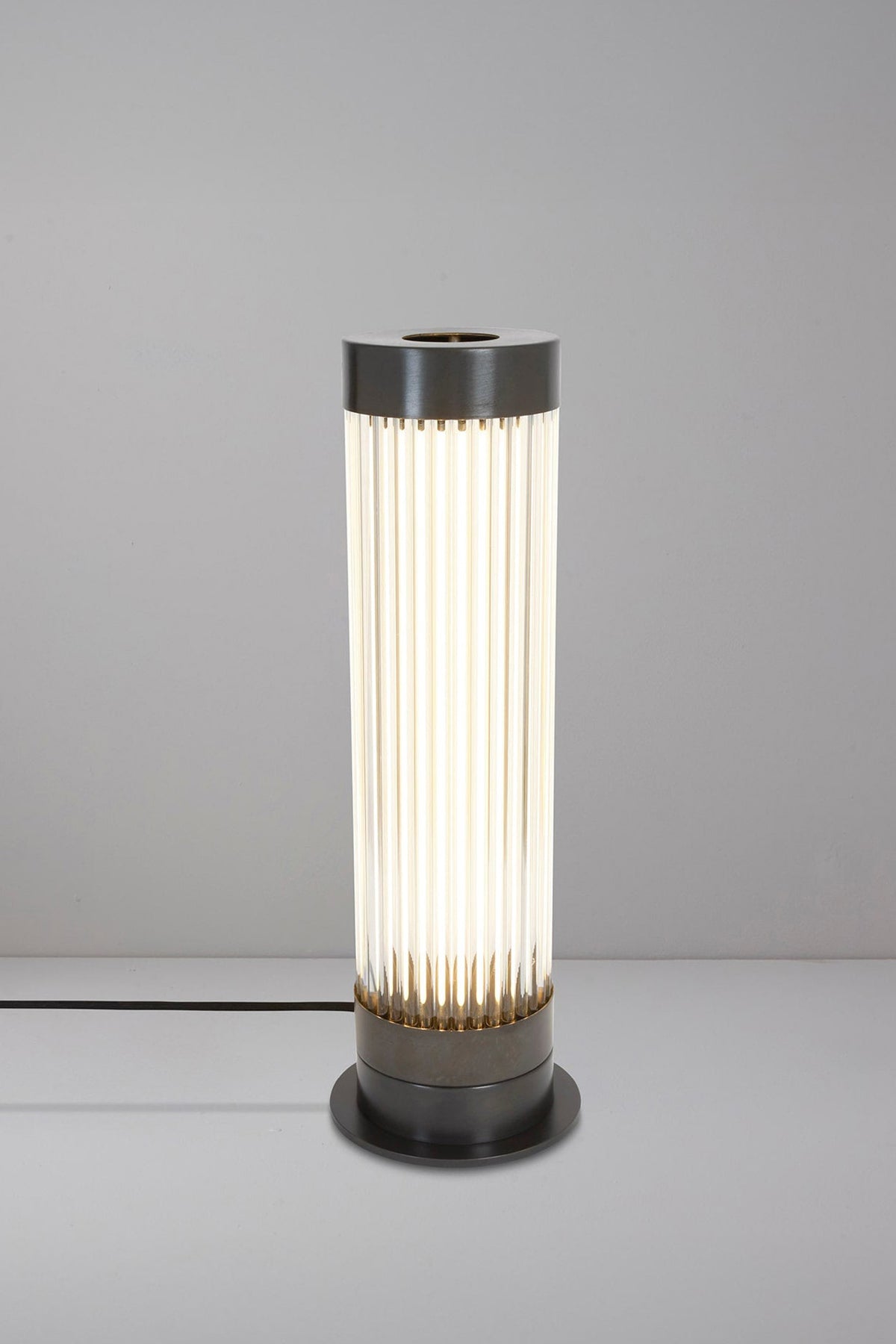 Pillar table light in weathered brass with glass.